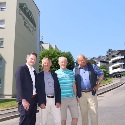 Das Bild zeigt die Führungsmitglieder der Baugenossenschaft vor einem ihrer Hochhäuser.