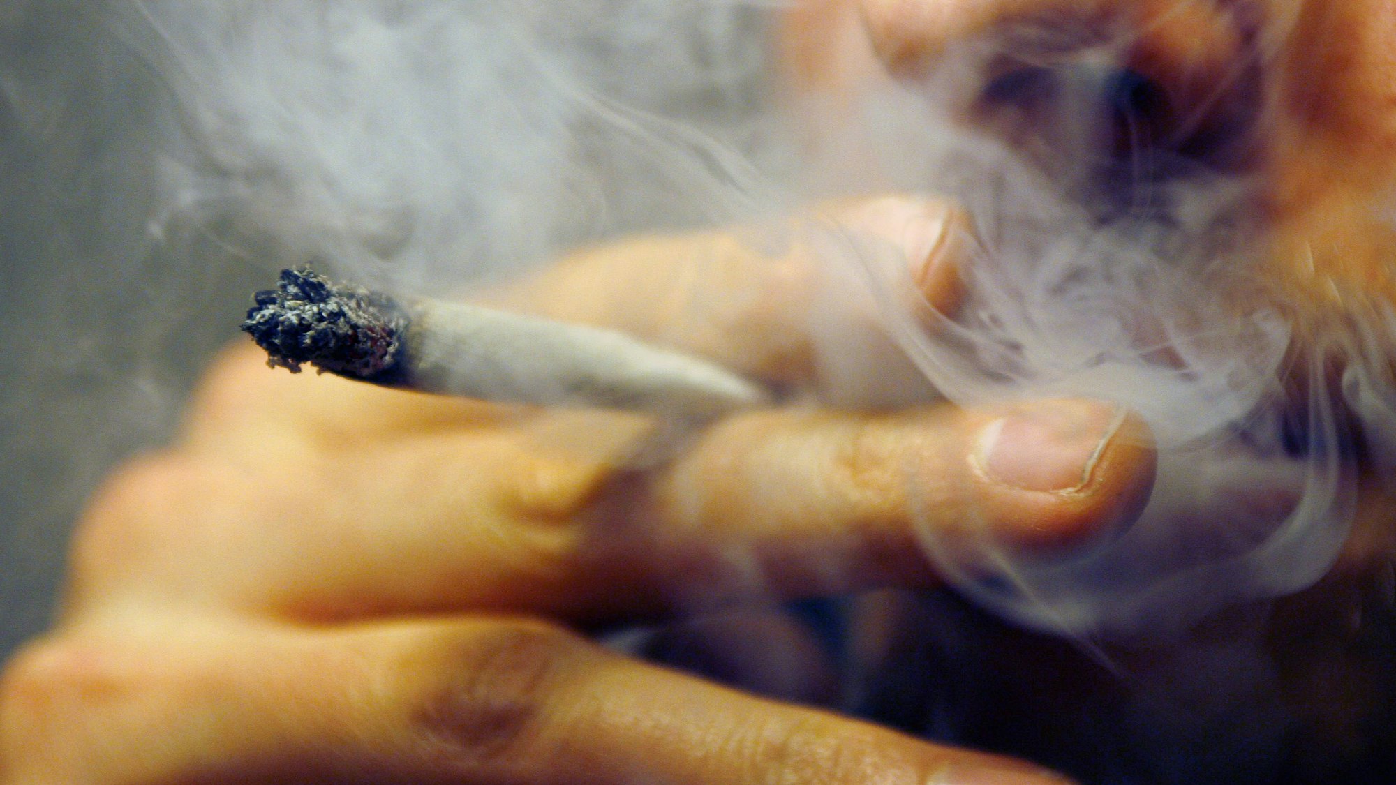 Ein Mann raucht einen Joint mit Marihuana.
