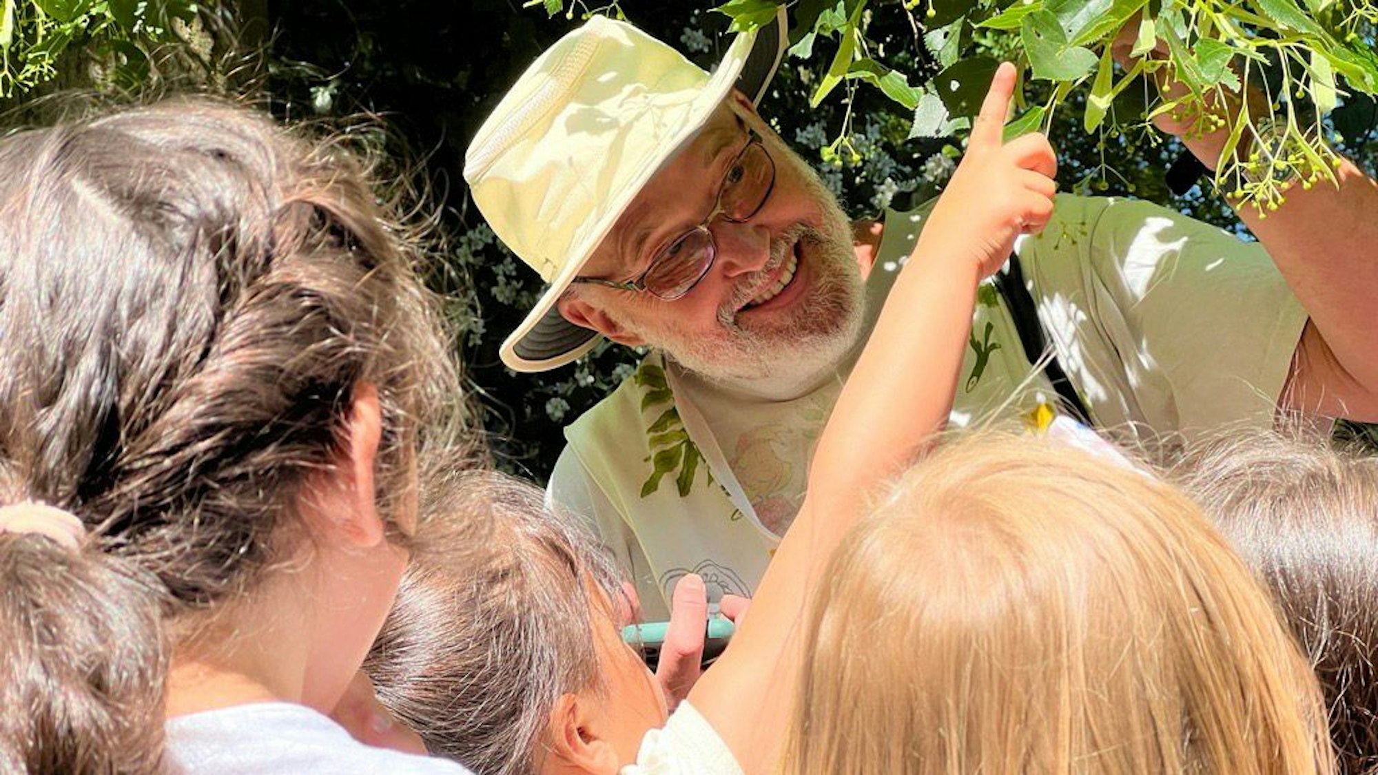 Manfred Urbschat, Stifter von „proNKids“, erklärt Kindern den Aufbau eines Lindenzweigs.