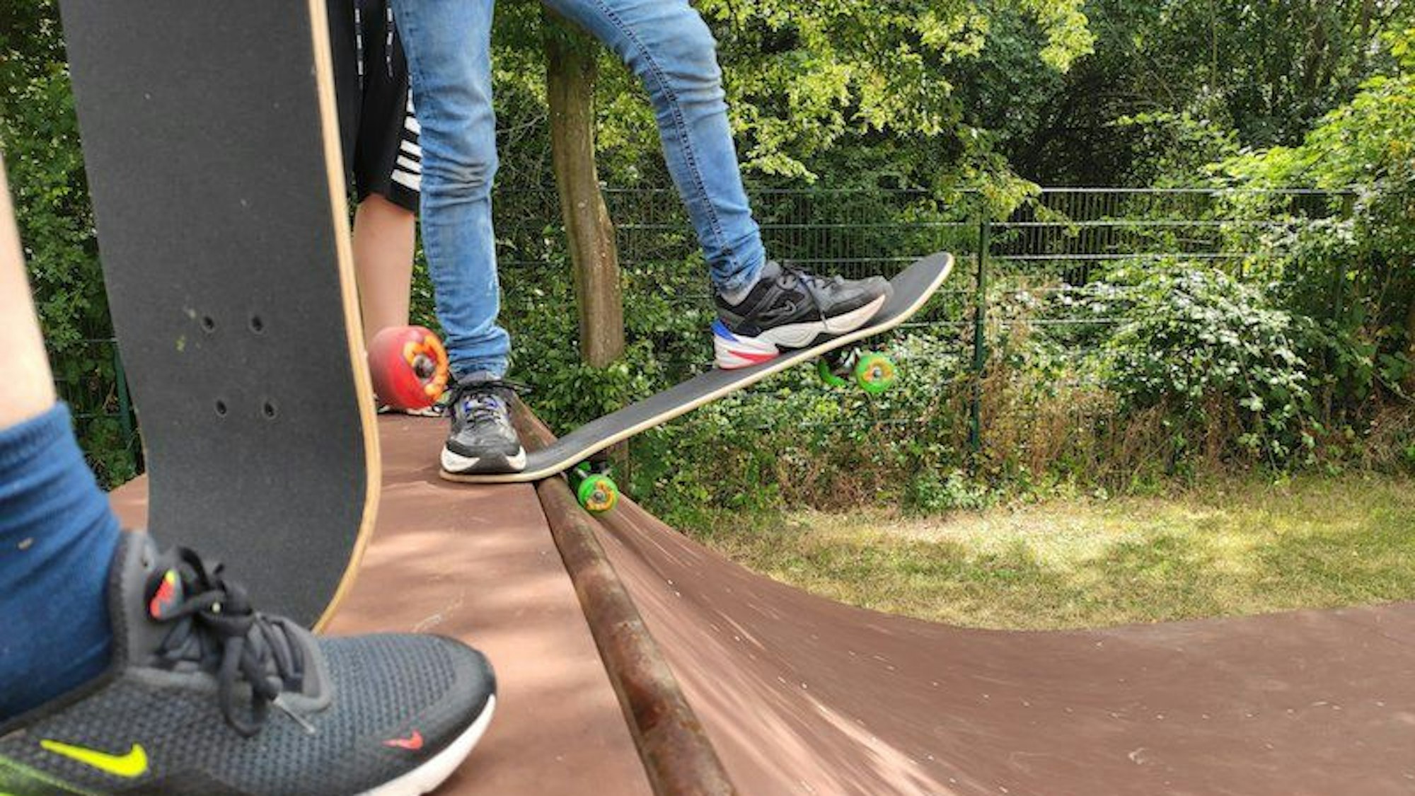 Drei Jugendliche stehen mit Skateboards auf einer Rampe.