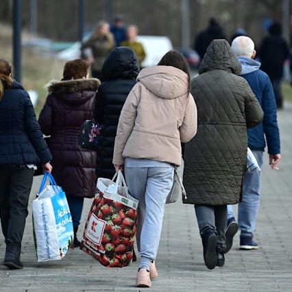 Ukrainische Flüchtlinge gehen nach ihrer Registrierung in der Orangerie der Biosphäre auf einem Weg entlang.