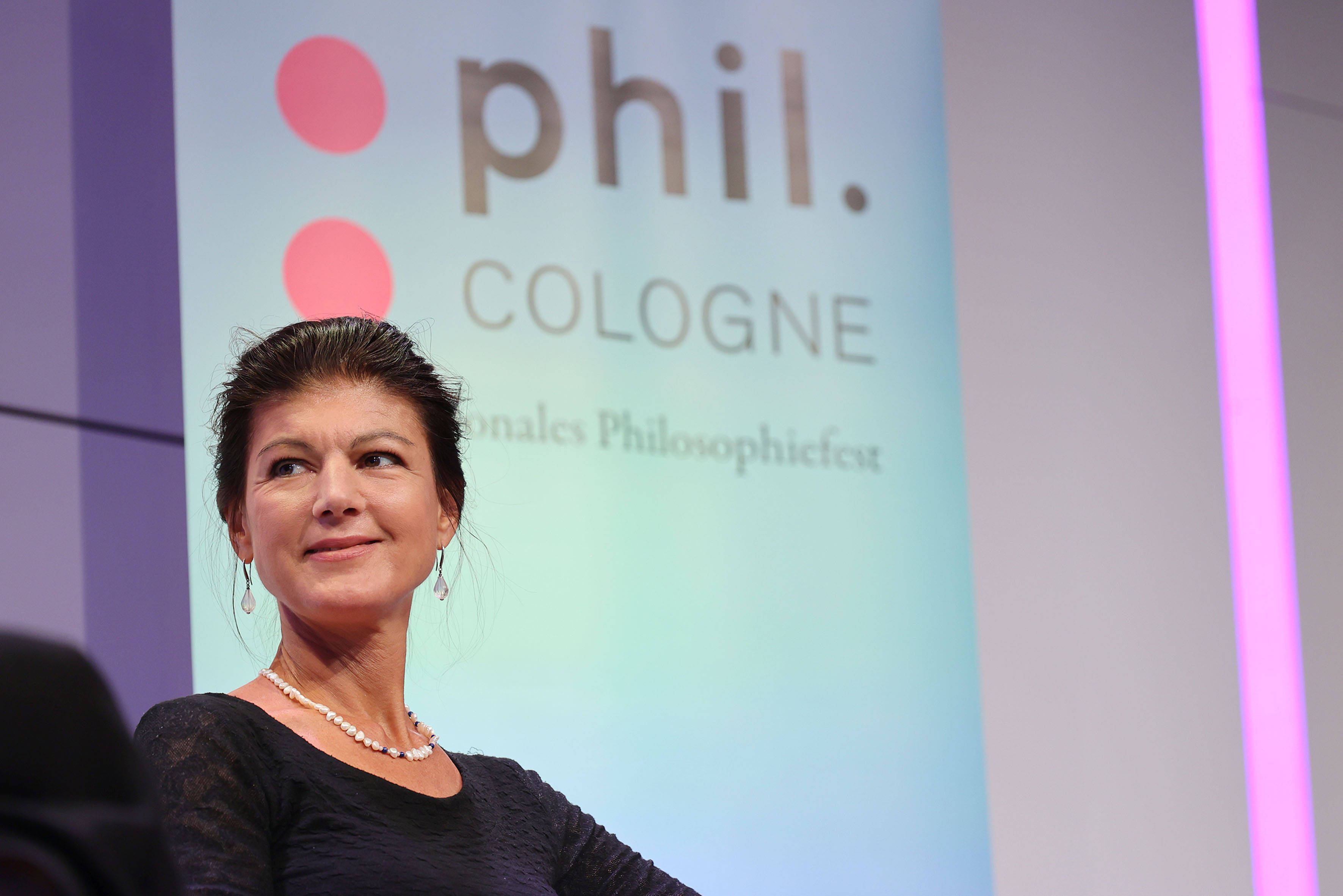 Die Politikern sitzt auf der Bühne, im Hintergrund ein Banner mit der Aufschrift „phil.Cologne. Internationales Philosophiefest“