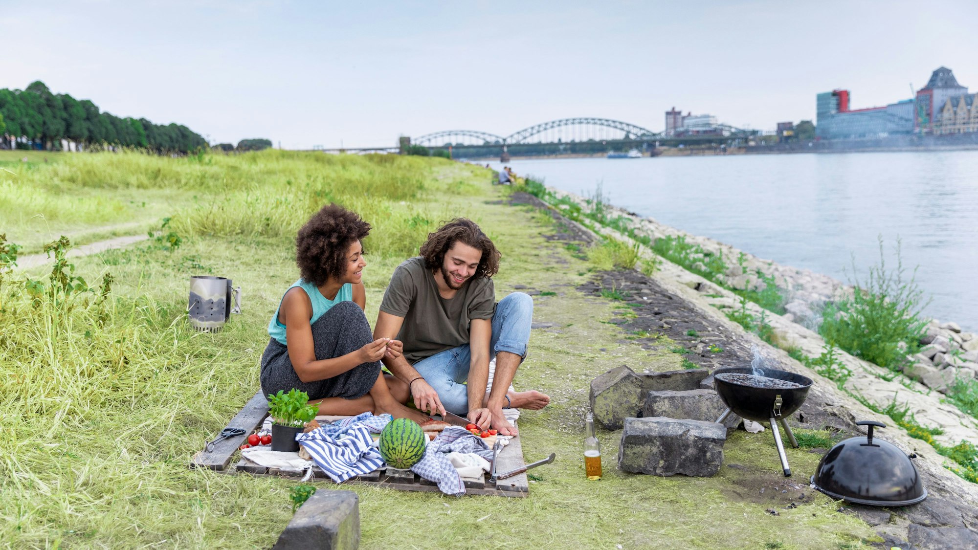 Eine Frau und ein Mann grillen am Kölner Rheinufer.