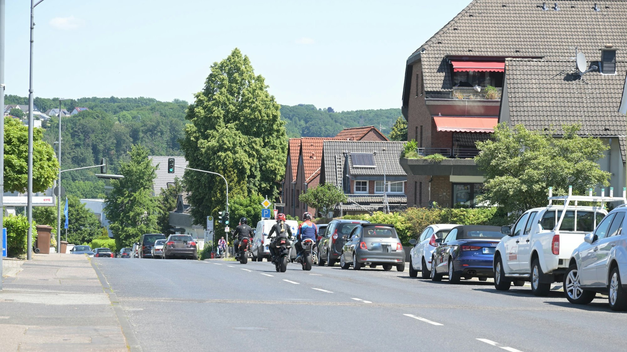 Autos parken auf der Altenberger-Dom-Straße und zwei Motorradfahrer fahre.