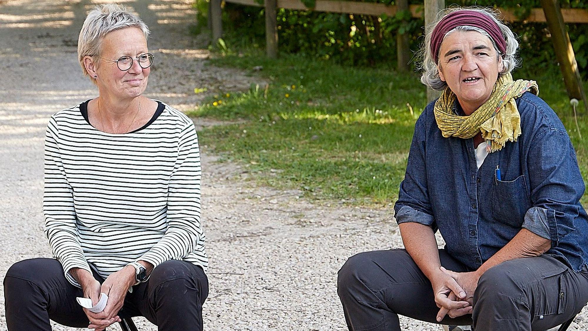 Die zwei Frauen Heidrun Grote und Ulrike Keuer sitzen auf ausklappbaren Hockern an einer Weggabelung in der Eifeler Natur.