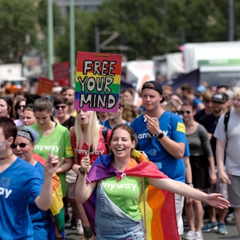Menschen bei der CSD-Demo in Köln mit bunten Schildern.