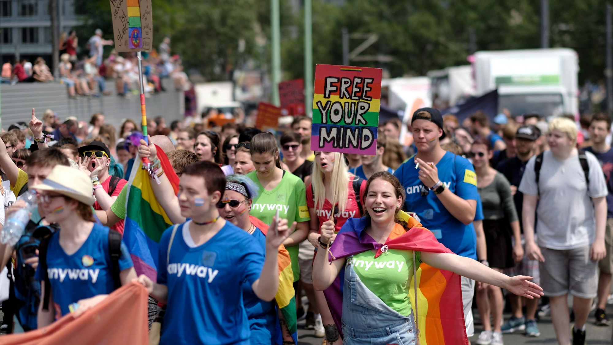 Menschen bei der CSD-Demo in Köln mit bunten Schildern.