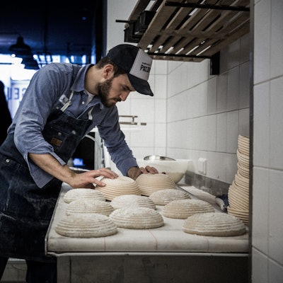 Max Kugel steht in seiner Backstube und stülpt bemehlte Brotteige auf eine Auslagefläche.
