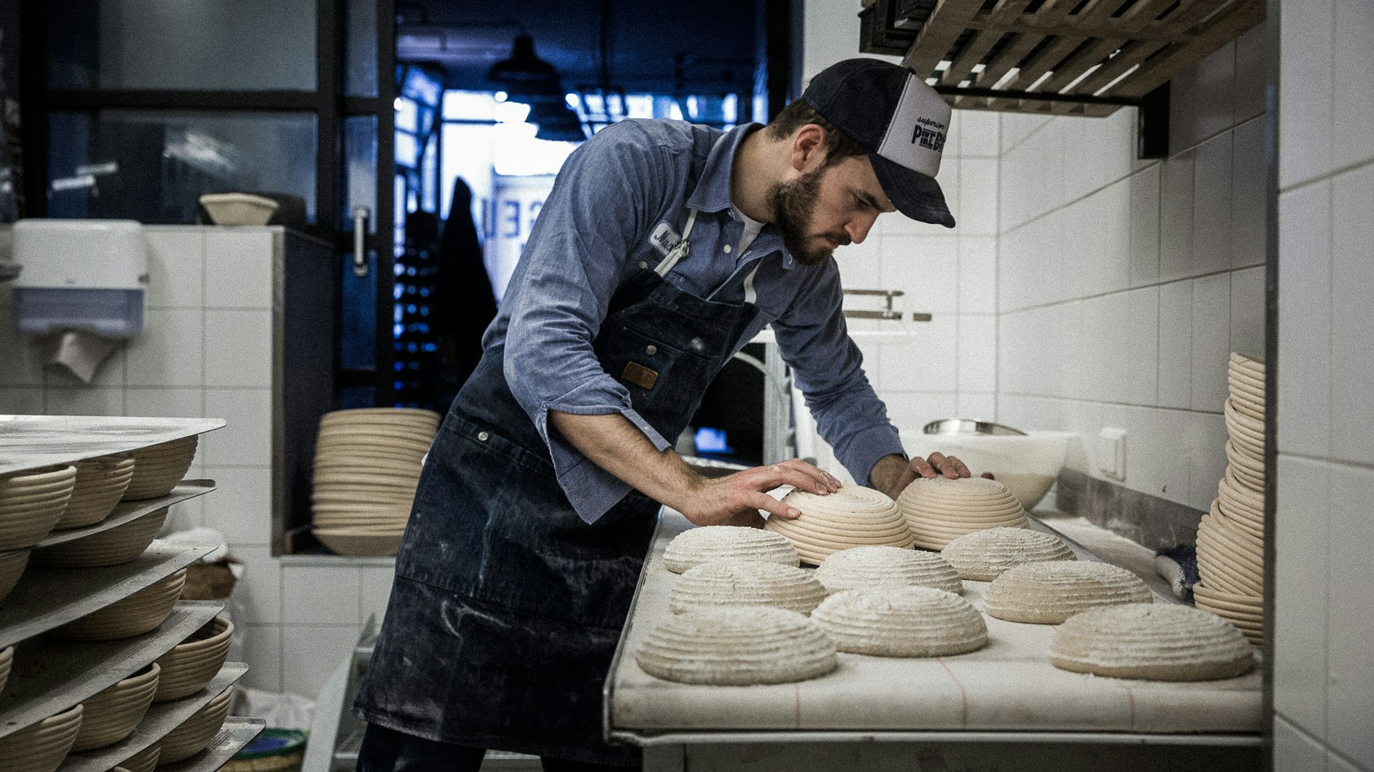 Max Kugel steht in seiner Backstube und stülpt bemehlte Brotteige auf eine Auslagefläche.