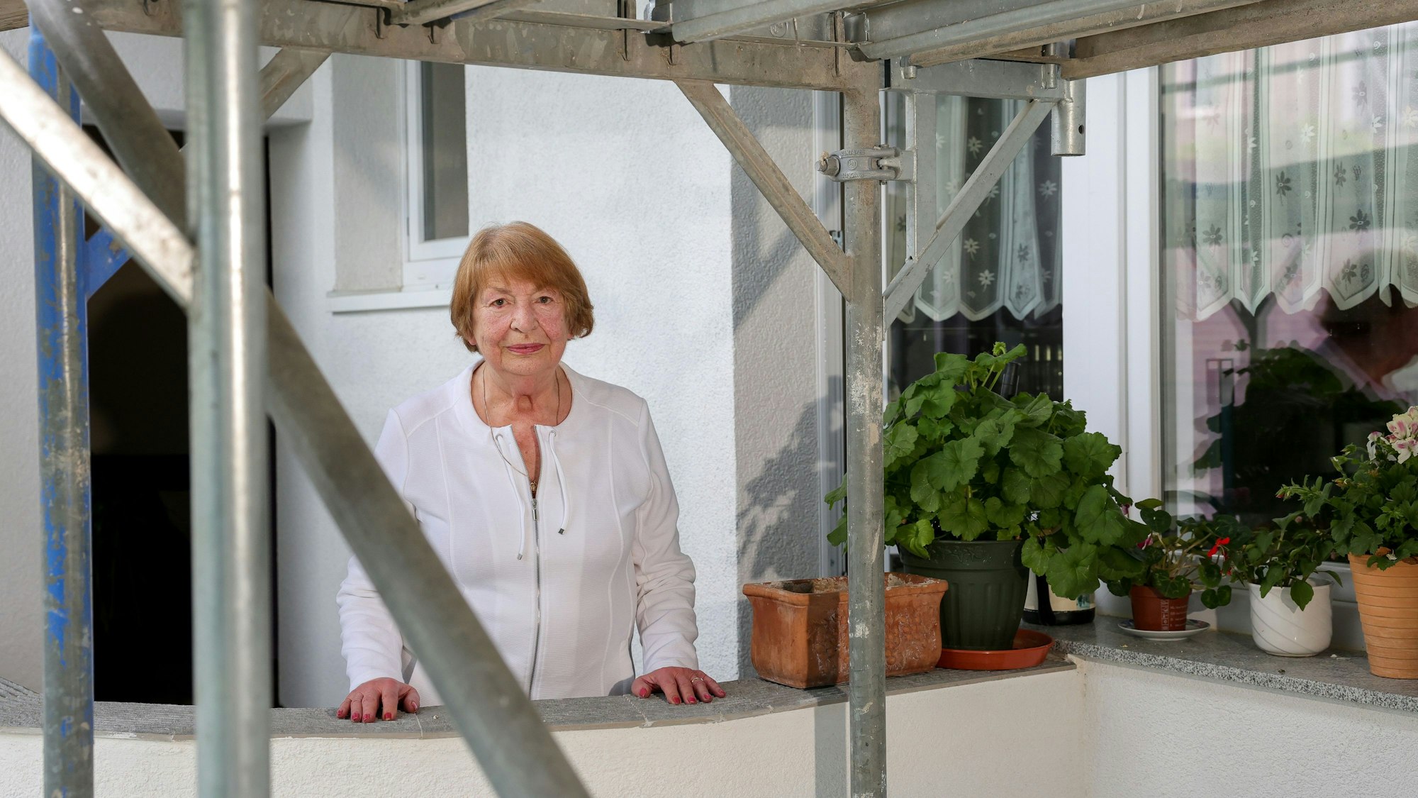 Porträt der 84-jährigen Luise Rühl-Schlömer, auf ihrem Balkon, davor ein Baugerüst