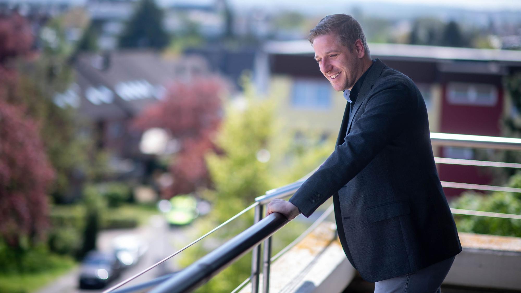 Landrat Markus steht auf dem Balkon am Kreishaus. Er lächelt.