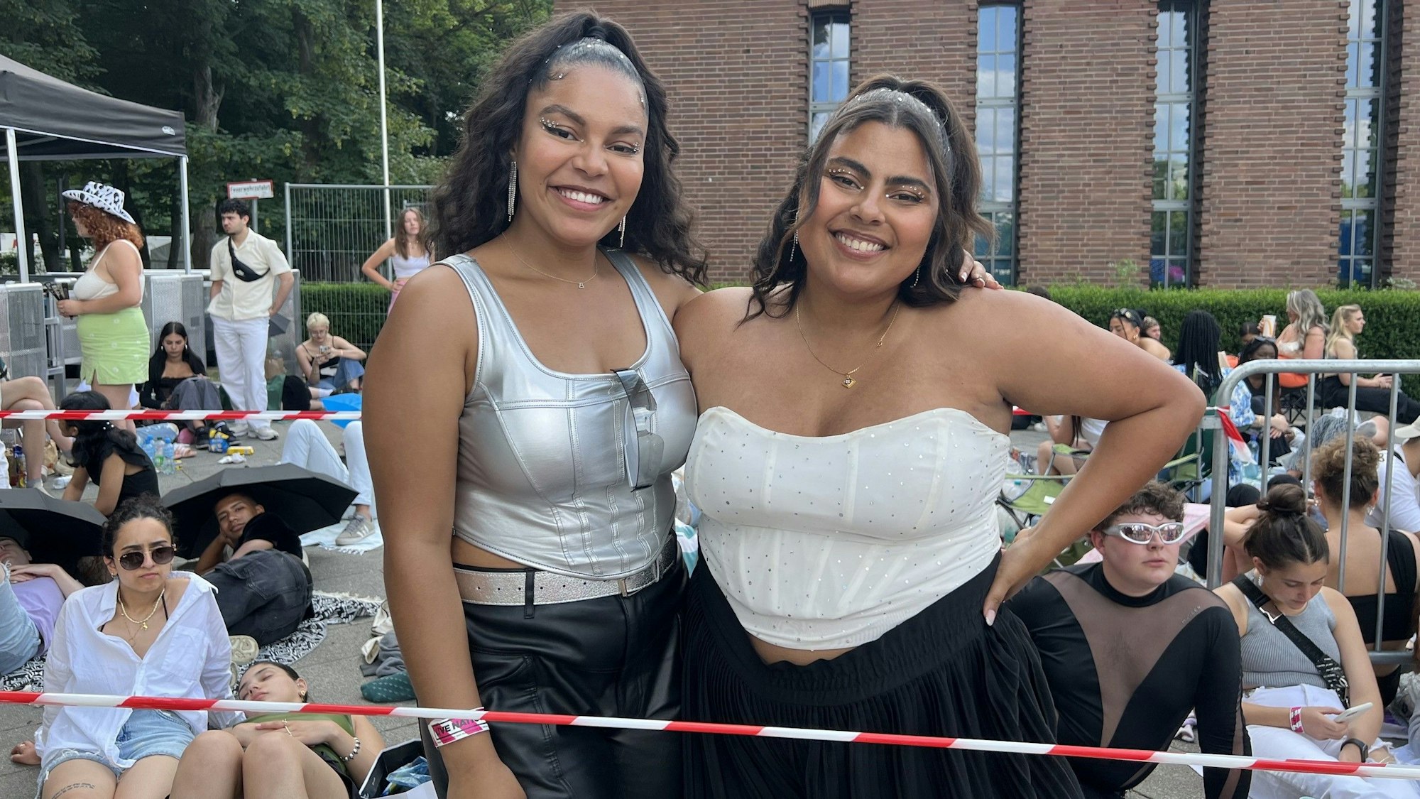 Zwei Frauen stehen Arm in Arm vorm Stadion.