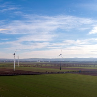 Eine Reihe von Windrädern stehen auf einem Feld.