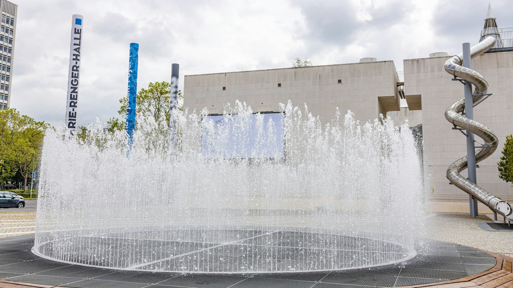 Ein Springbrunnen spritzt Wasser vor der Bundeskunsthalle. Am Rand stehen 16 Säulen, die die Bundesländer symbolisieren.