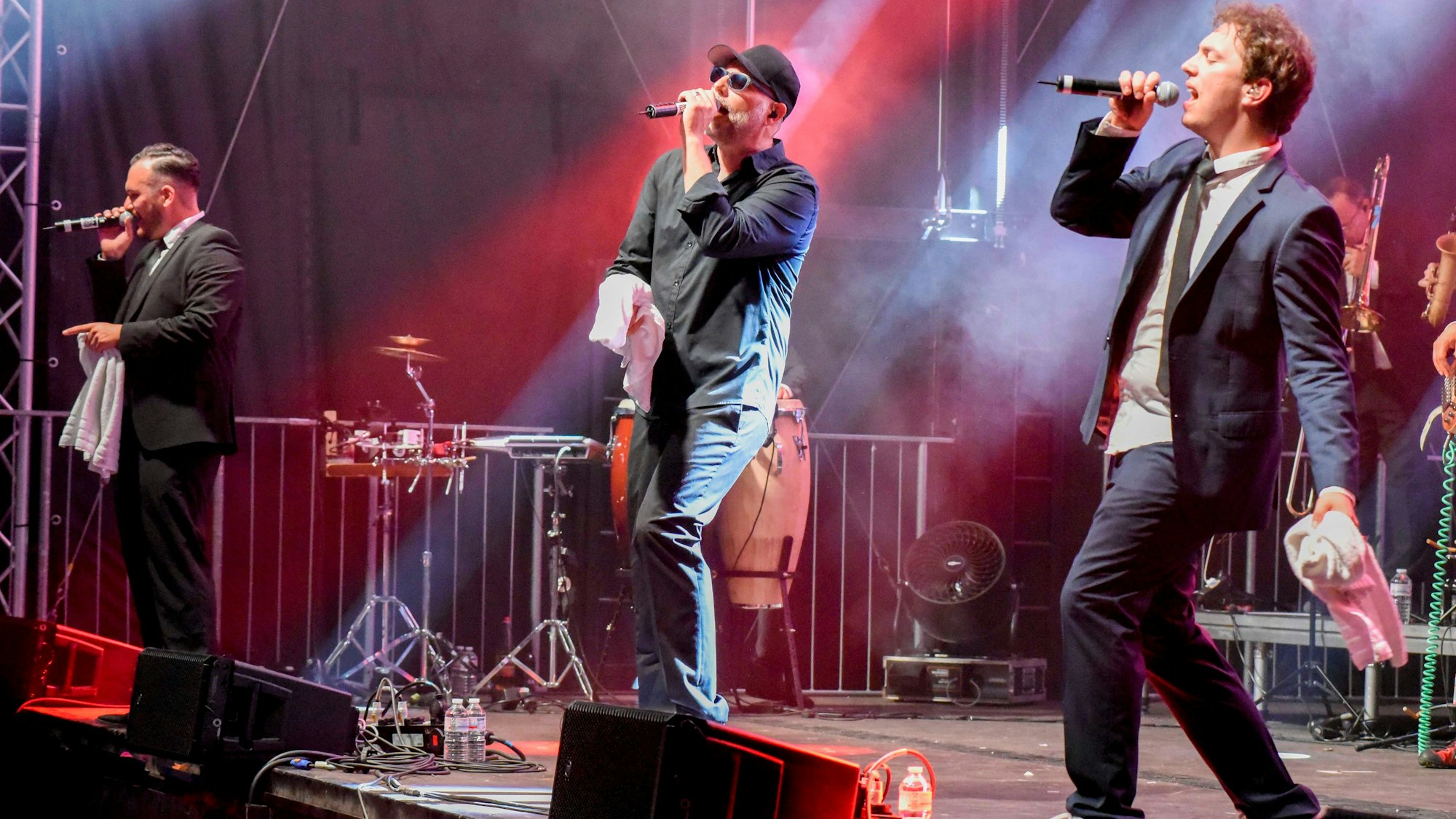 Auftritt der Music Monkeys bei Summer in the City. Drei Männer singen in Mikrofone auf einer Bühne.