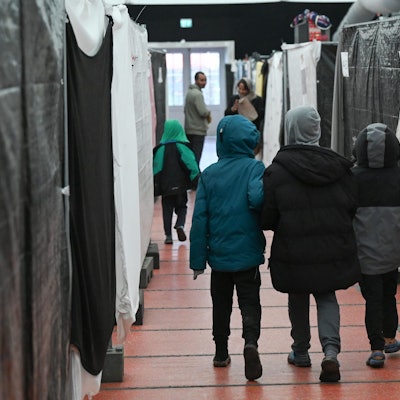 Drei Flüchtlingskinder gehen durch ein Zelt der Flüchtlingsunterkunft im hessischen Bensheim.