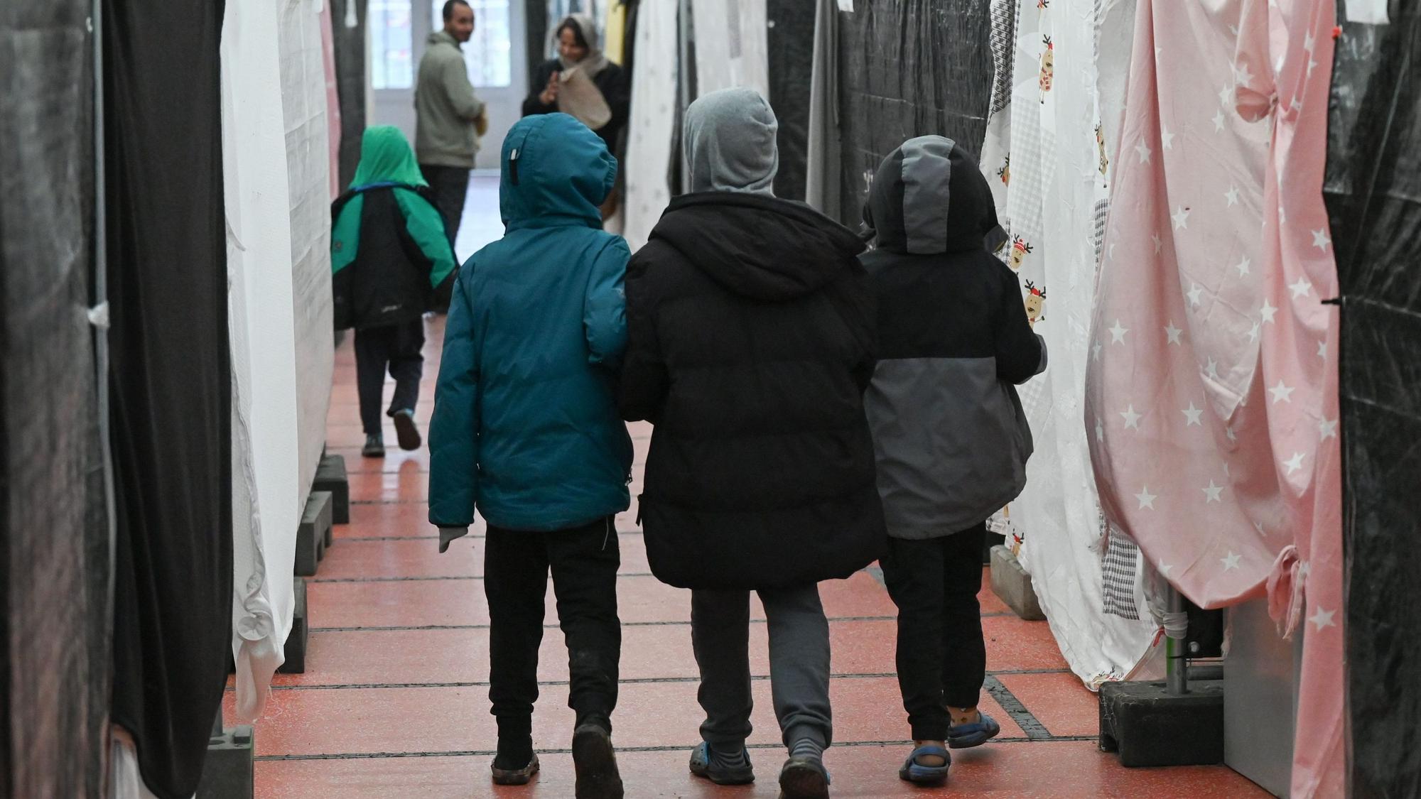 Drei Flüchtlingskinder gehen durch ein Zelt der Flüchtlingsunterkunft im hessischen Bensheim.