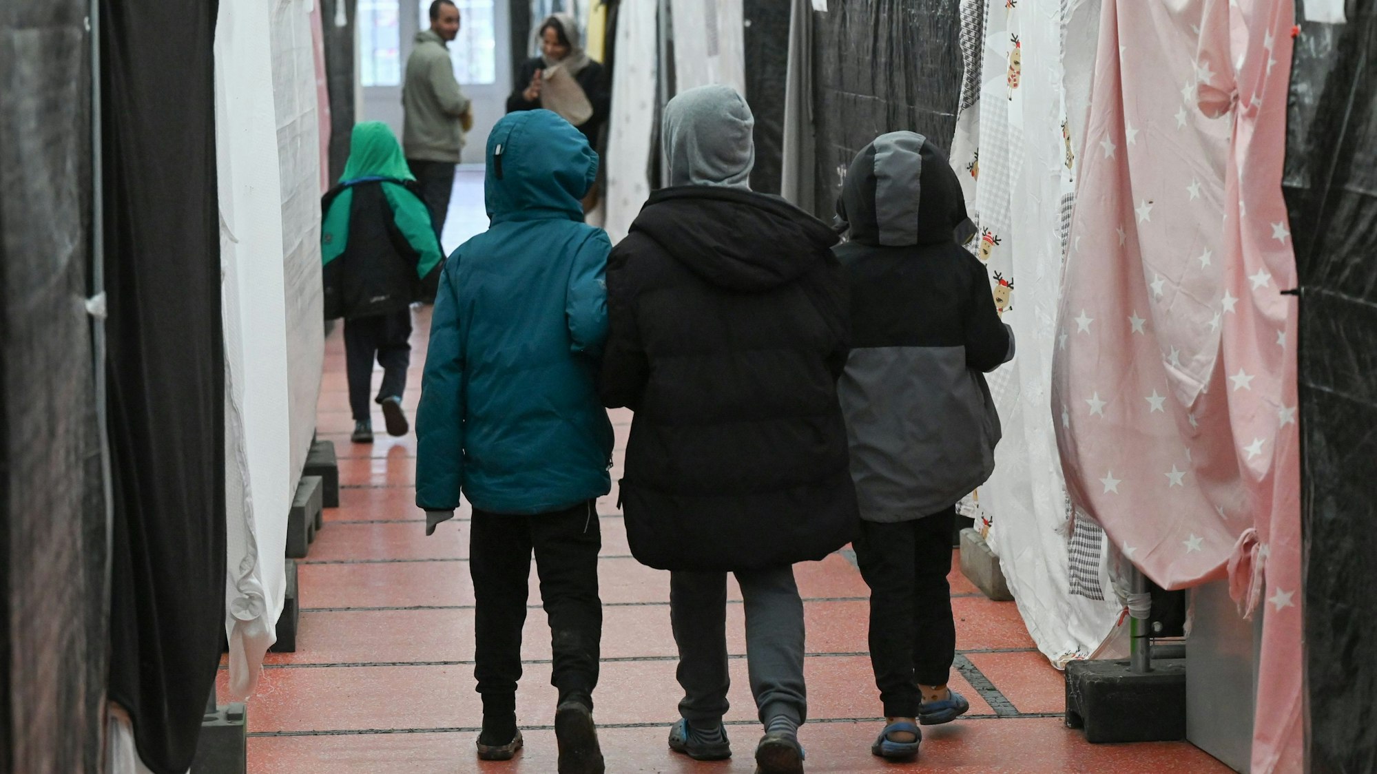 Drei Flüchtlingskinder gehen durch ein Zelt der Flüchtlingsunterkunft im hessischen Bensheim.