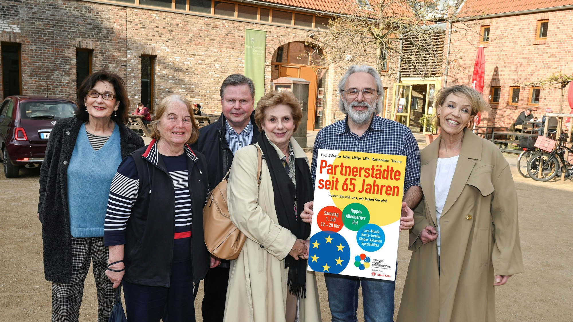 Vertreterinnen und Vertreter der Fördervereine mit einem Plakat vor dem Altenberger Hof in Nippes