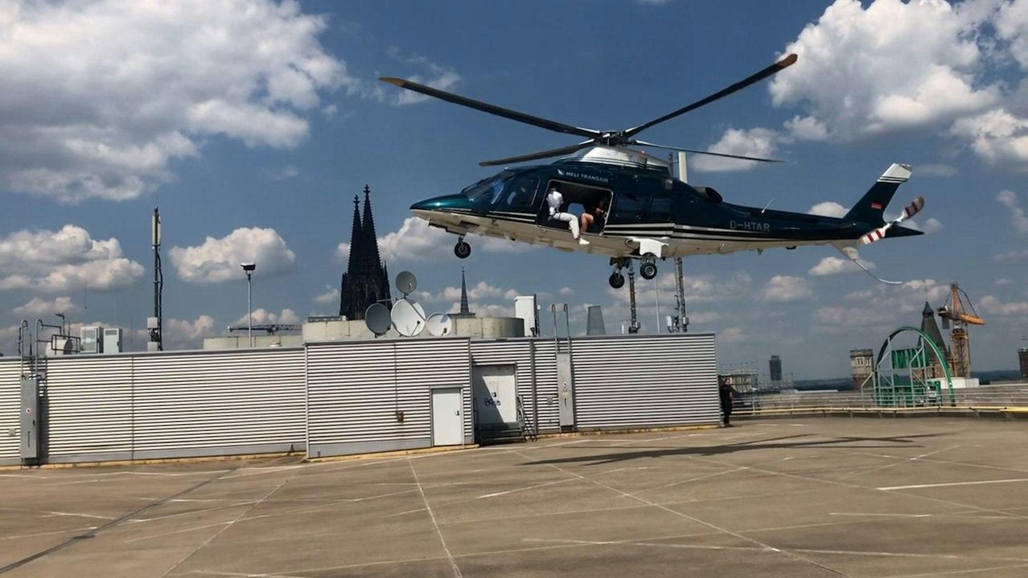 Ein Influencer sitzt in einem Helikopter über dem Parkdeck von Galeria Kaufhof in der Kölner Innenstadt.