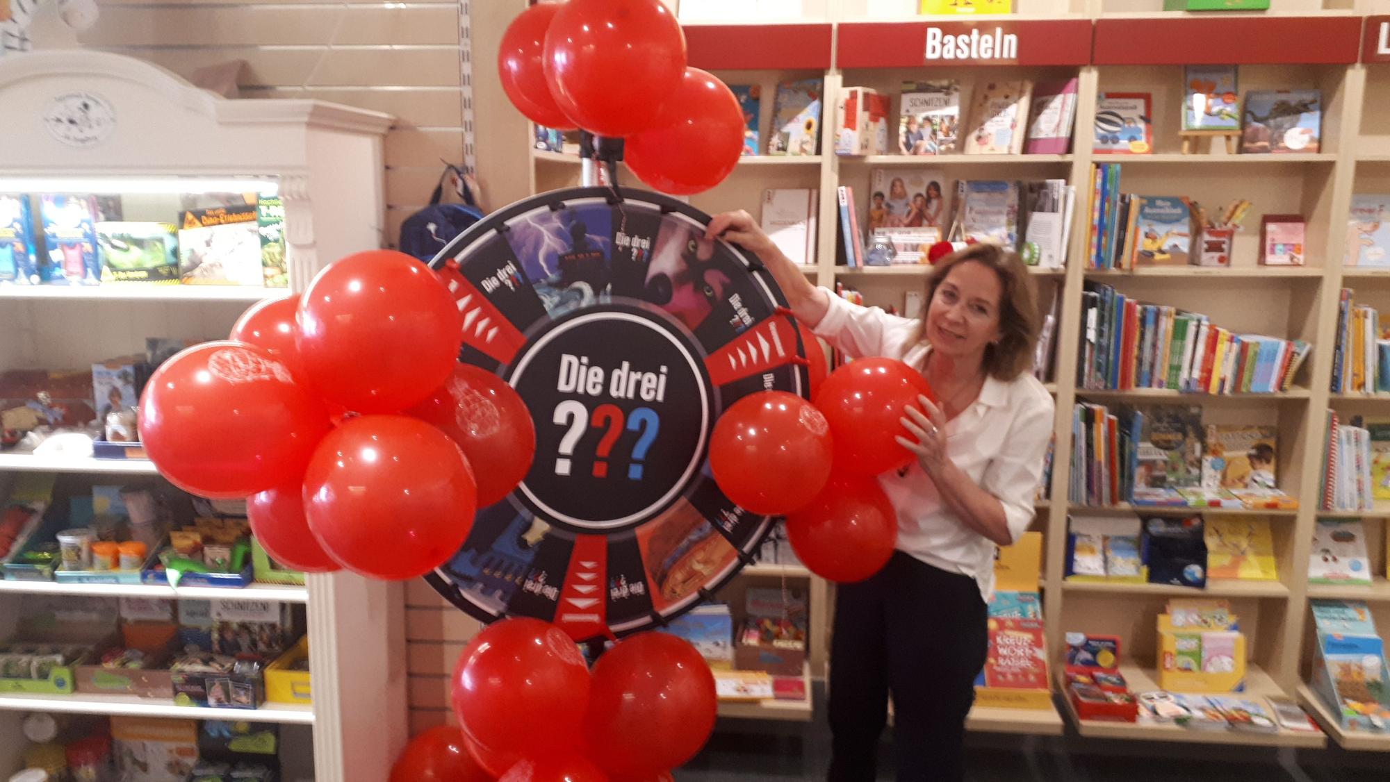 Christiane Blut dreht an einem Gewinnrad der „Drei Fragezeichen“ in der Buchhandlung.