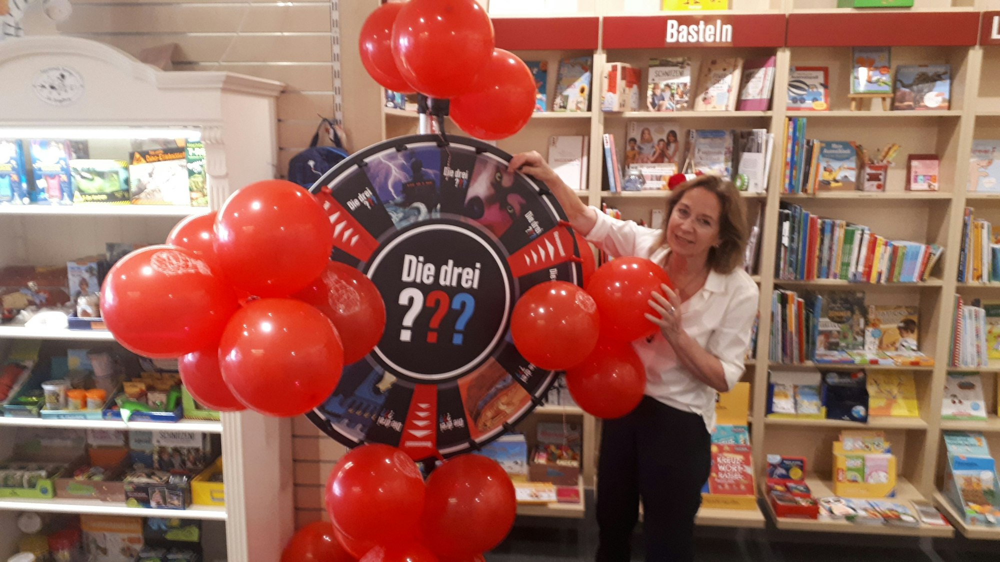 Christiane Blut dreht an einem Gewinnrad der „Drei Fragezeichen“ in der Buchhandlung.