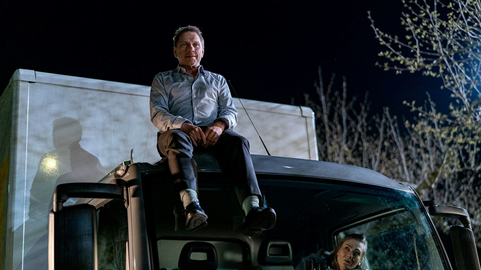 Lannertz sitzt auf einem LKW, die verwirrte Jessy schaut aus dem Inneren des Wagens zu ihm hinauf.