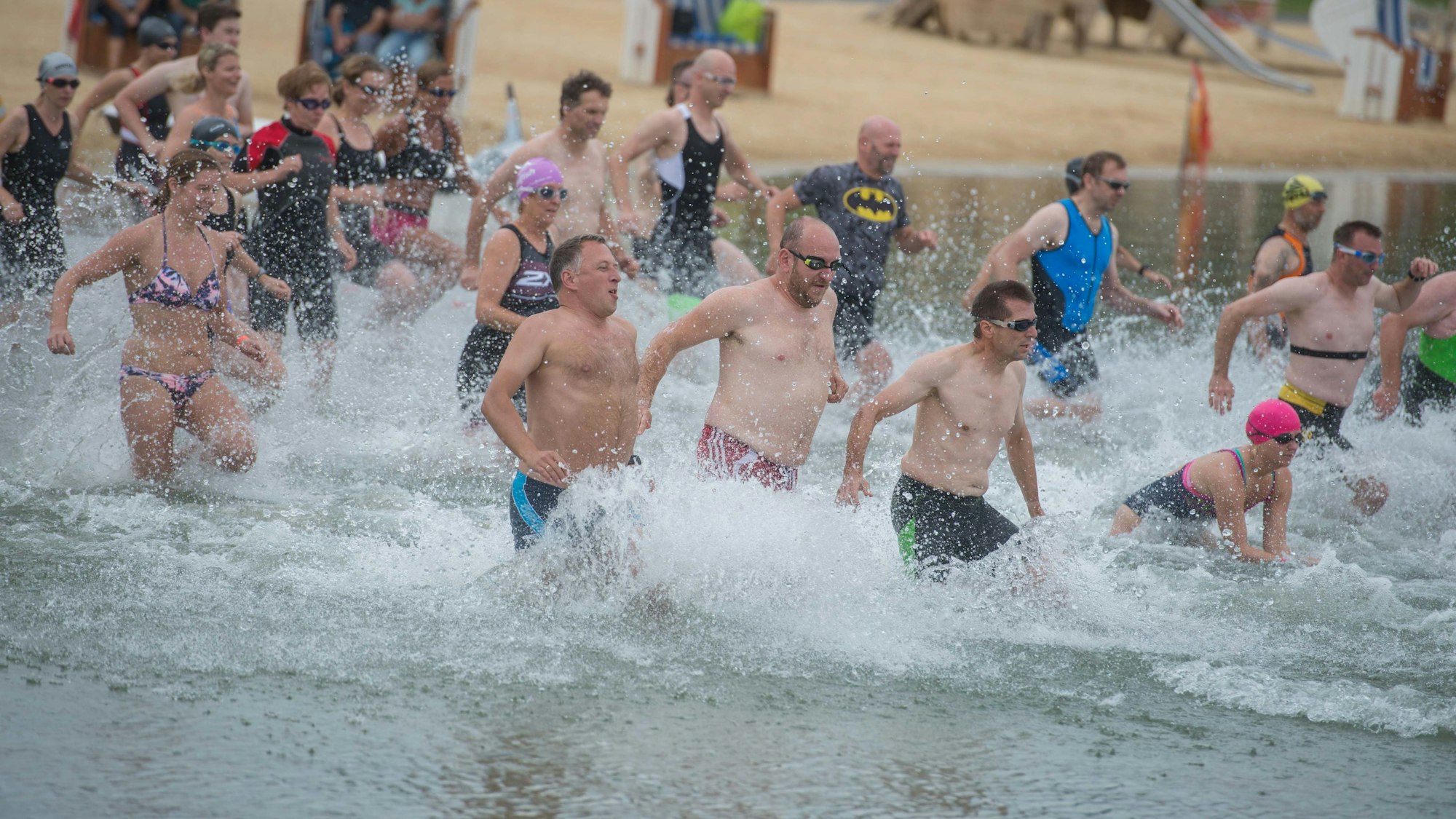 Menschen in Badekleidung laufen für einen Triathlon in den Zülpicher Wassersportsee.