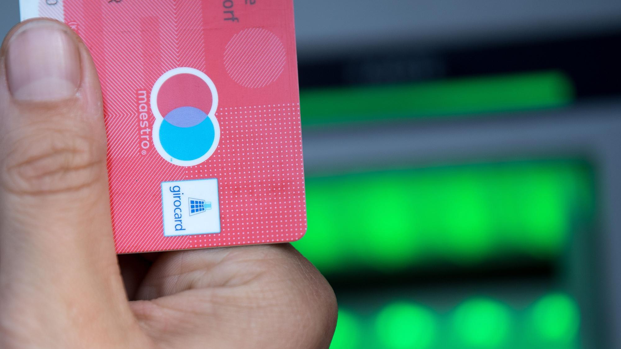 Eine Bankkundin hebt mit ihrer Girokarte Bargeld von einem Geldautomaten ab.