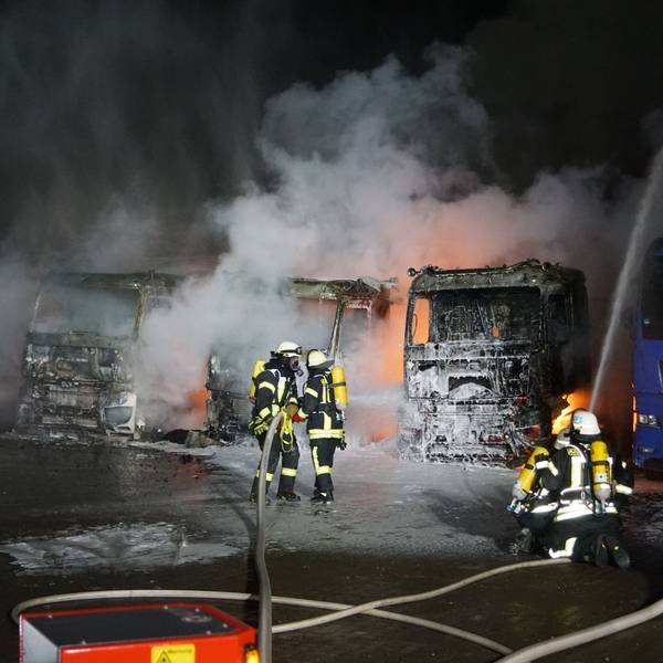 Das Bild zeigt sechs Feuerwehrleute, wie sie brennende Lkw löschen.