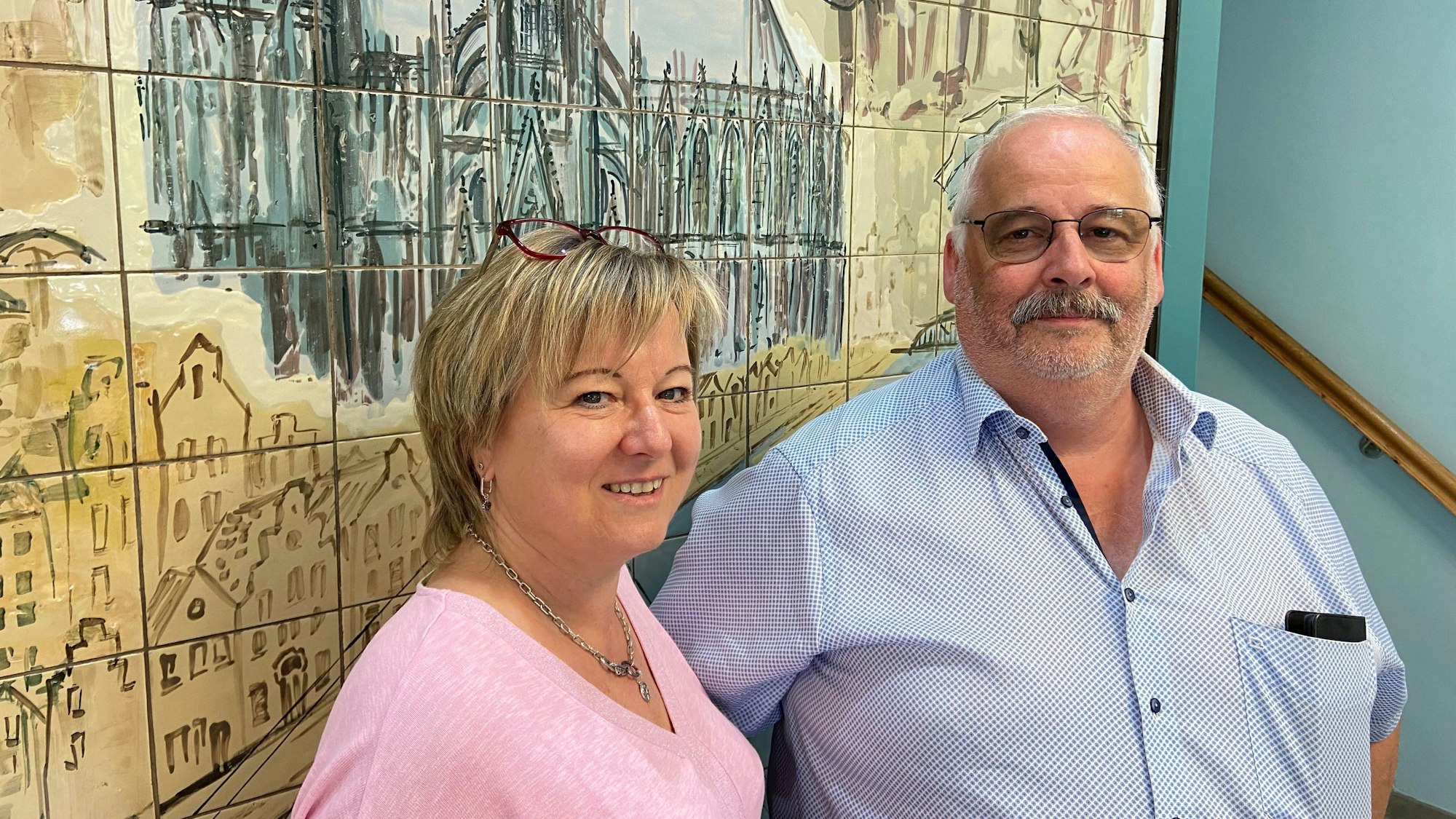 Das Ehepaar steht nebeneinander und lächelt in die Kamera.