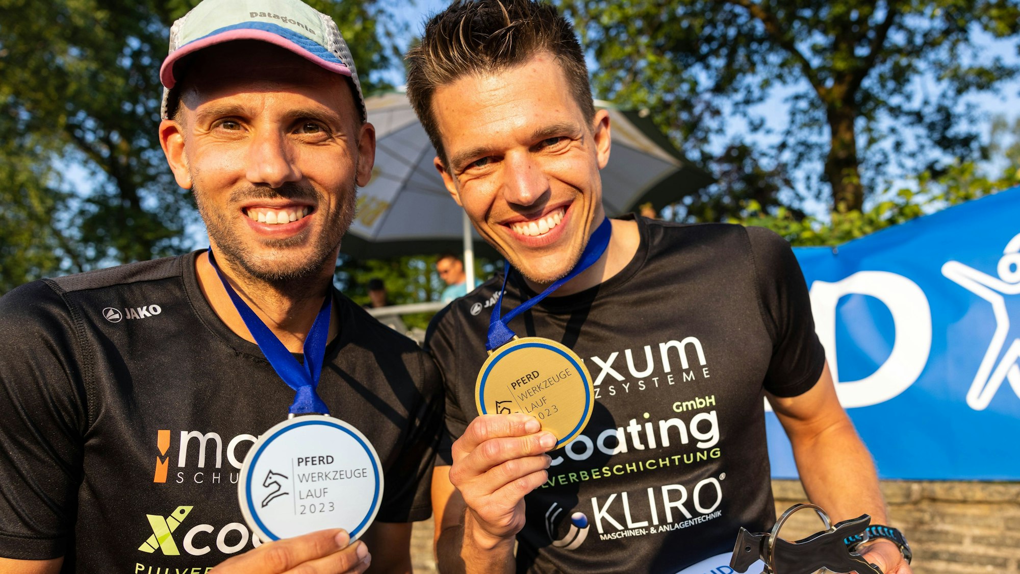 Im Bild sind zwei junge Männer, die ihre Medaillen präsentieren.