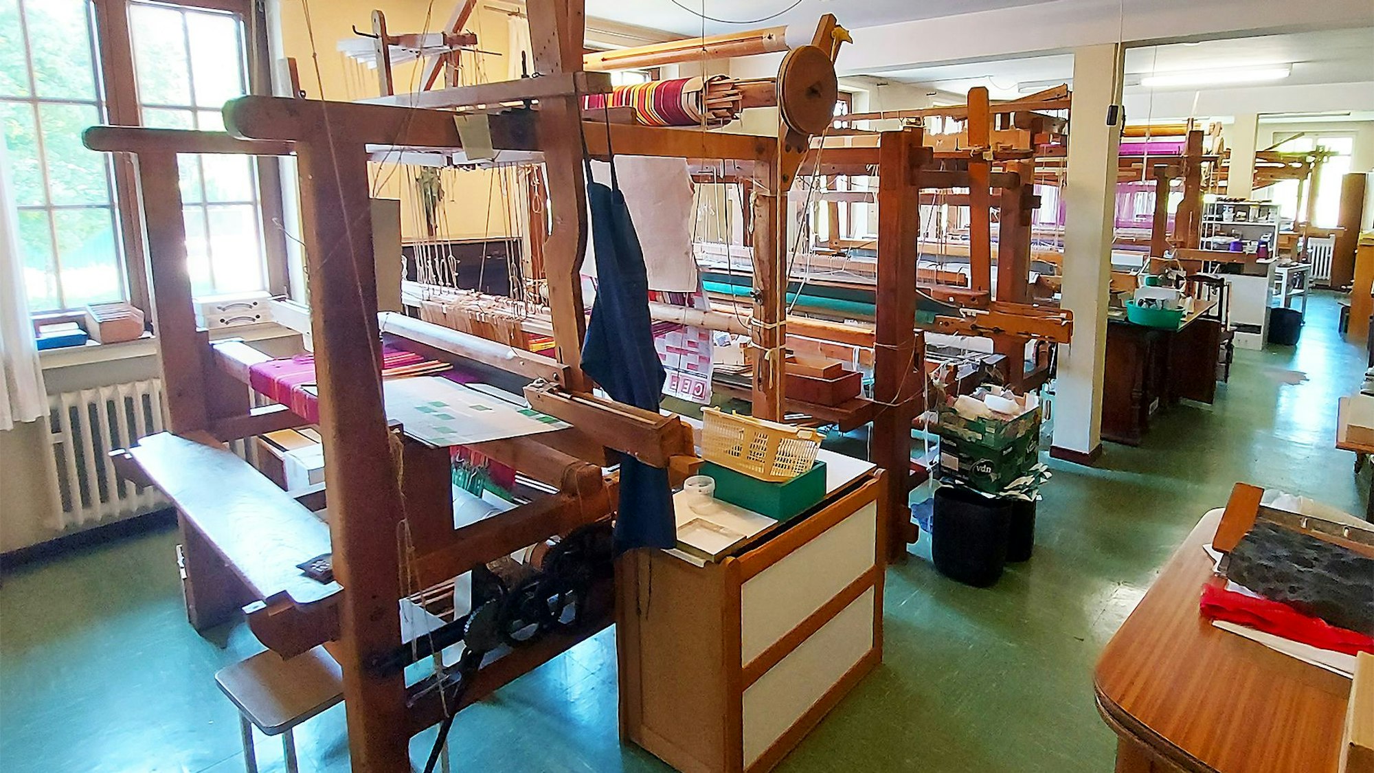 Sechs alte Handwebstühle stehen in einem Saal eines ehemaligen Klosters.