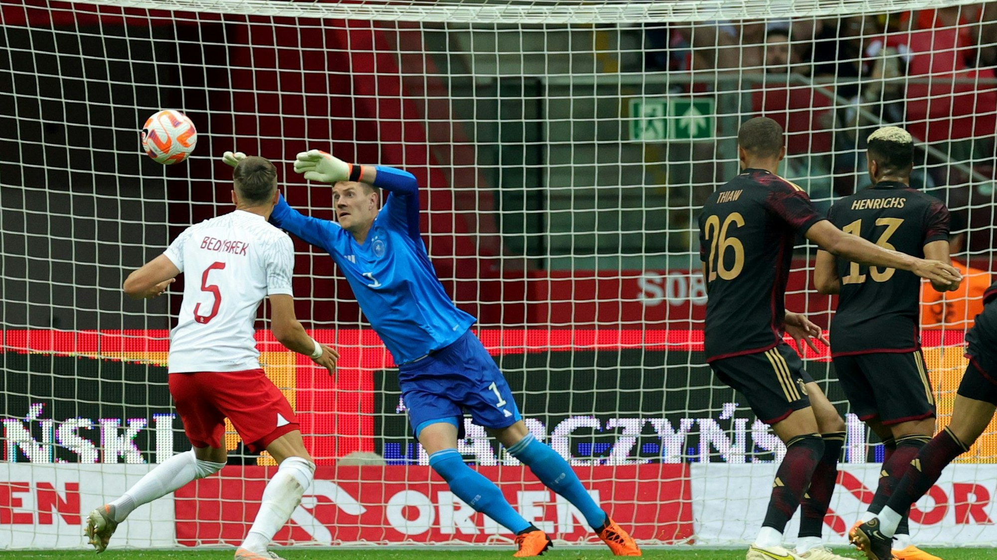 Ein Torwart spring in Richtung des anfliegenden Fußballs in die rechte Torecke.