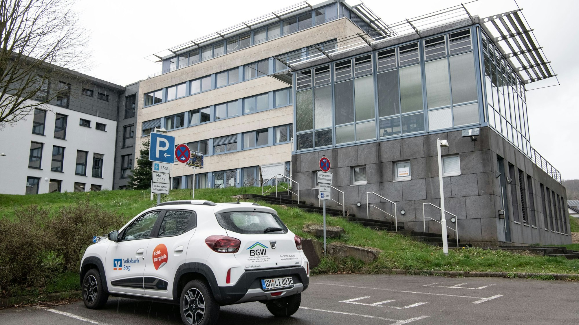 Das Rathaus Lindlar ist im Hintergrund zu sehen, vorne steht ein weißes Auto.