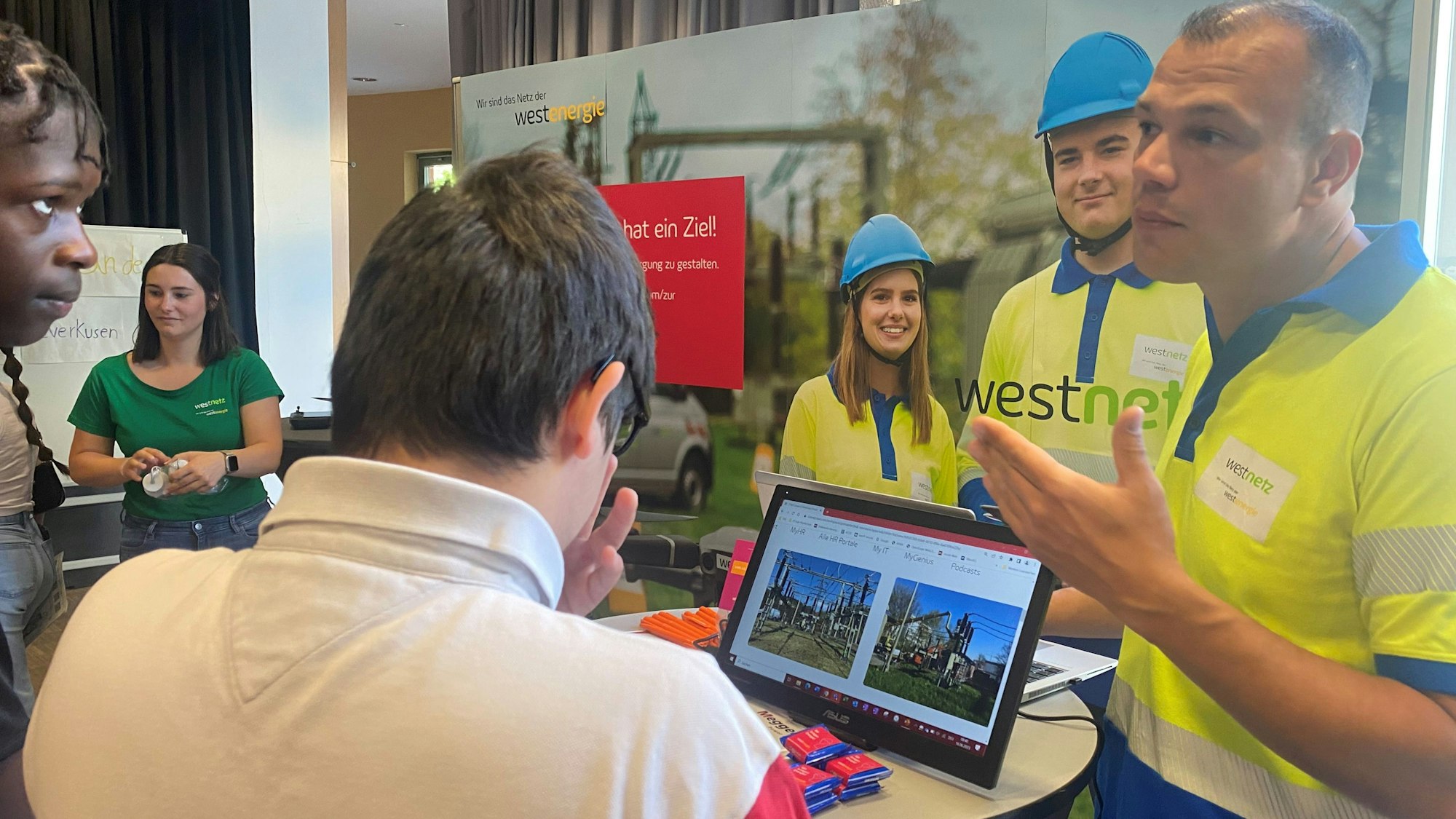 Berufsmesse an der Sekundarschule Leverkusen: Westenergie-Mitarbeiter Alexander Cuk erklärt Batuham (weißes Shirt) und Joel (l.) etwas.
