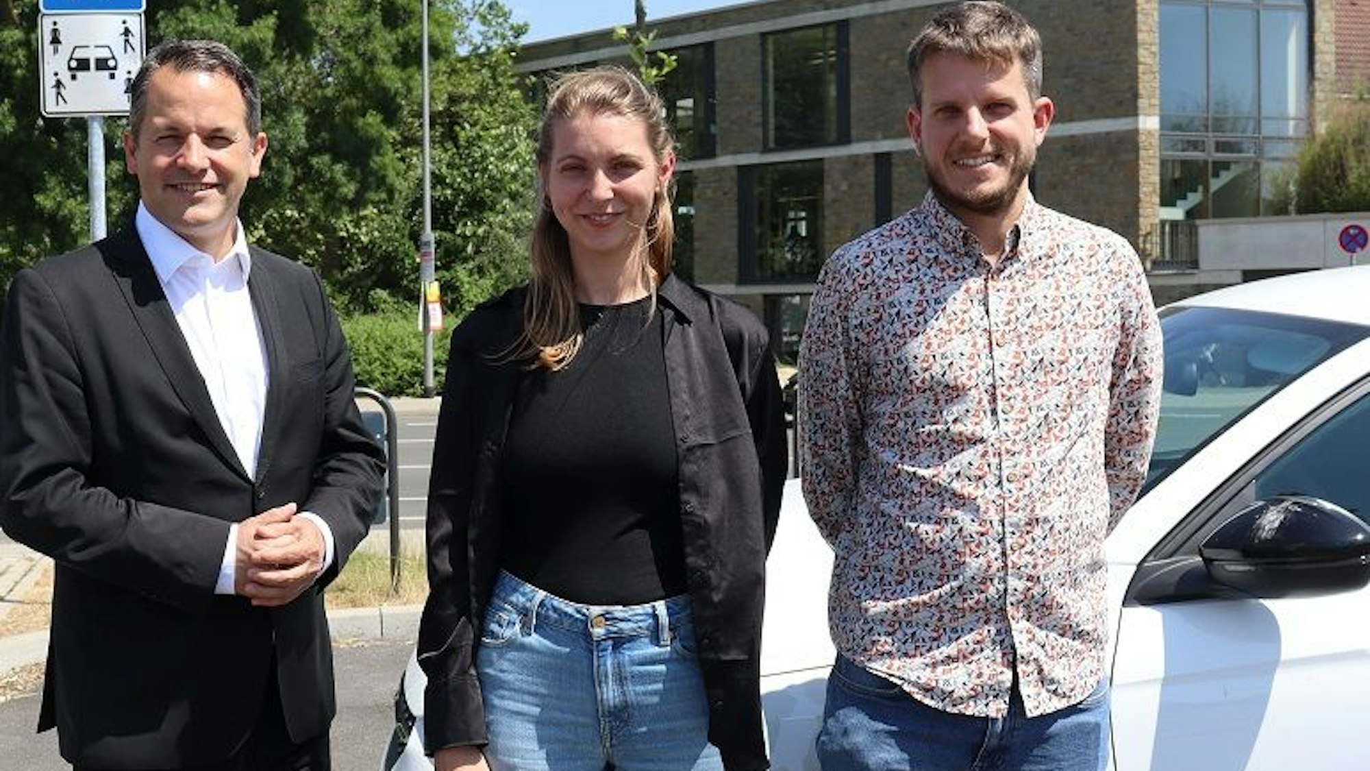Bürgermeister Frank Keppeler (v.l.) hat sich mit Klimaschutzmanagerin Jana van Kranenbrock und Mobilitätsmanager Thomas Bette ein Bild vor Ort gemacht. Alle drei schauen, vor einem Auto stehend, in die Kamera.