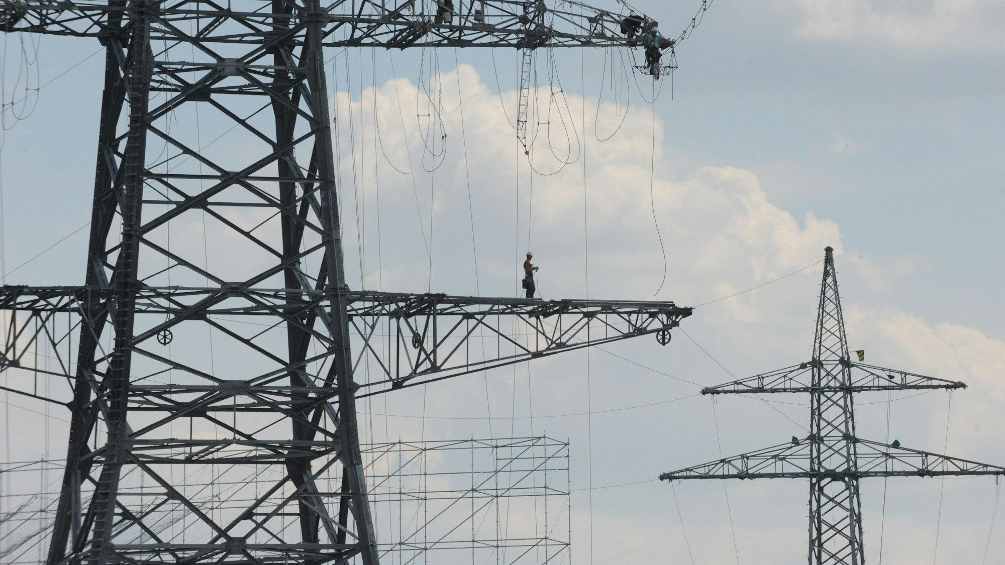Das Foto zeigt einen Arbeiter auf einem Hochspannungsmast.