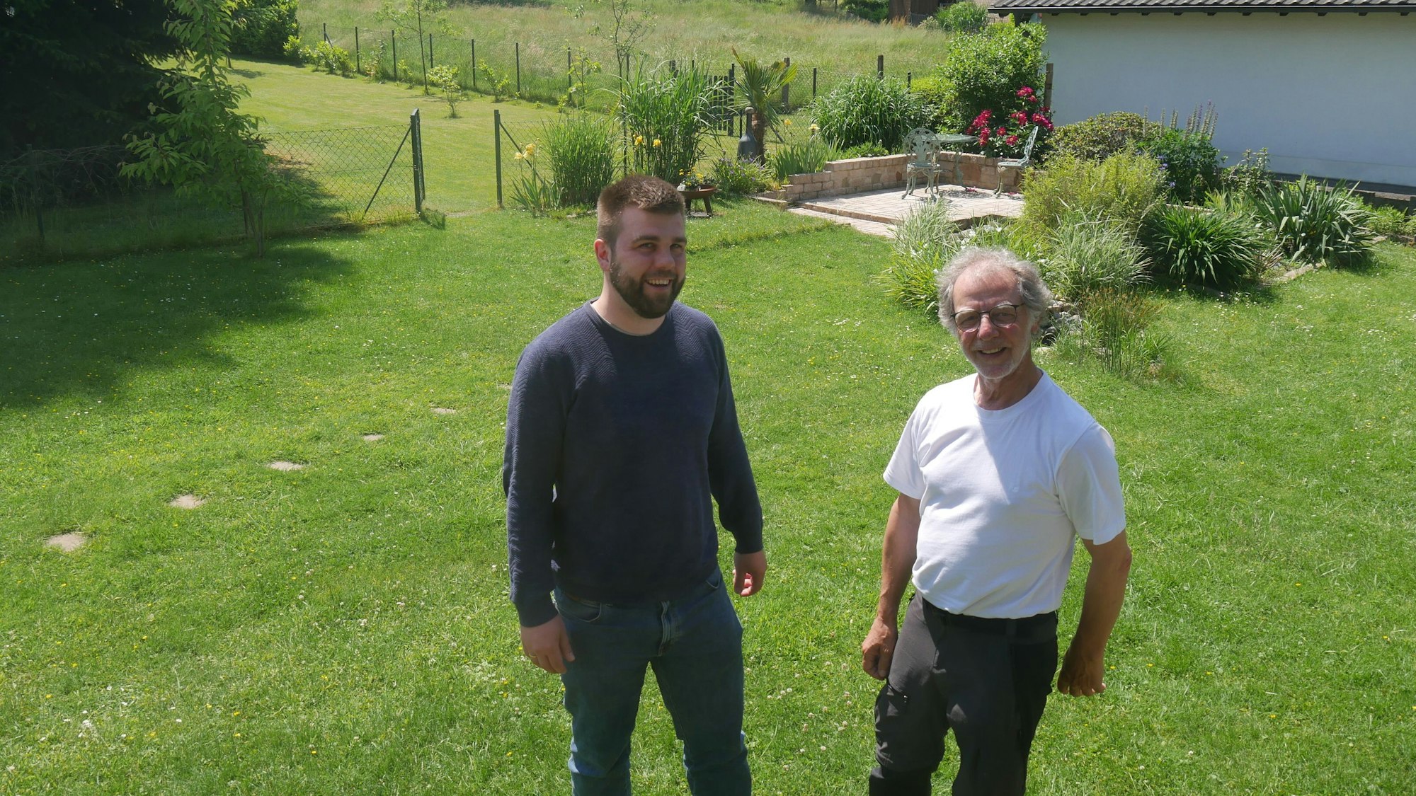 Luca Schwarzer und Ferdinand Patt stehen nebeneinander auf einer Wiese und lachen in die Kamera.