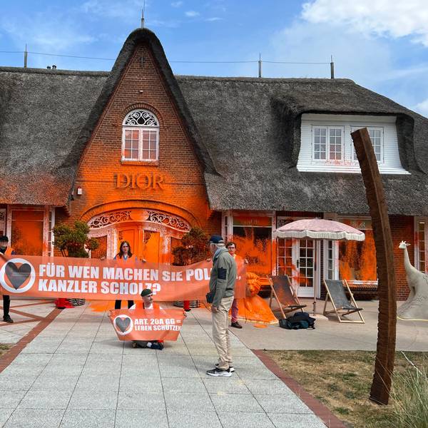 Klima-Aktivisten haben sich vor einem besprühten Luxusgeschäft auf der Insel Sylt platziert