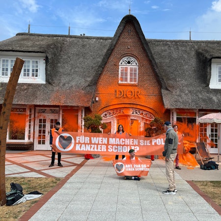 Klima-Aktivisten haben sich vor einem besprühten Luxusgeschäft auf der Insel Sylt platziert