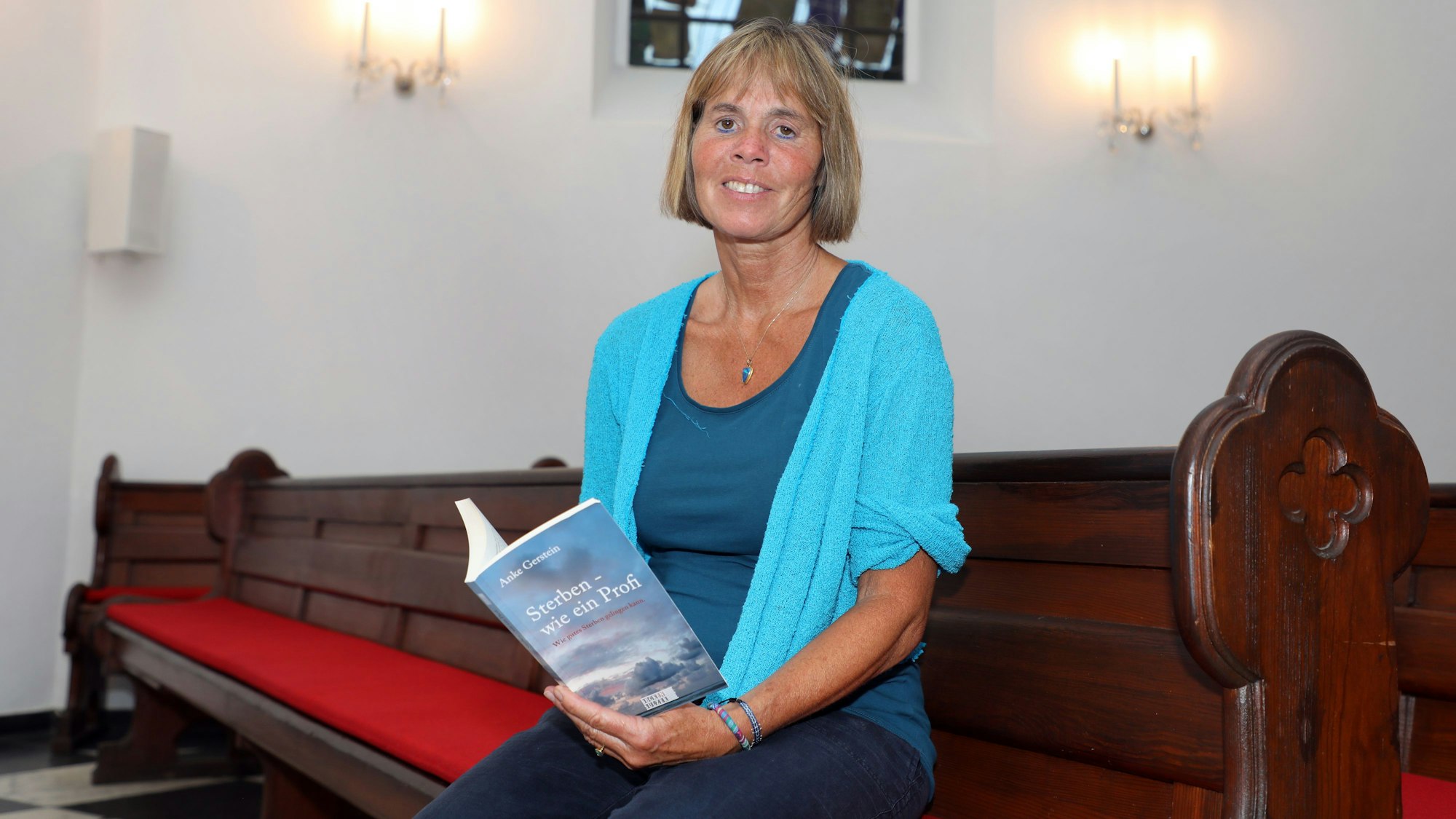 Die Autorin Anke Gerstein sitzt in einer Bank der Evangelischen Gnadenkirche in Bergisch Gladbach.