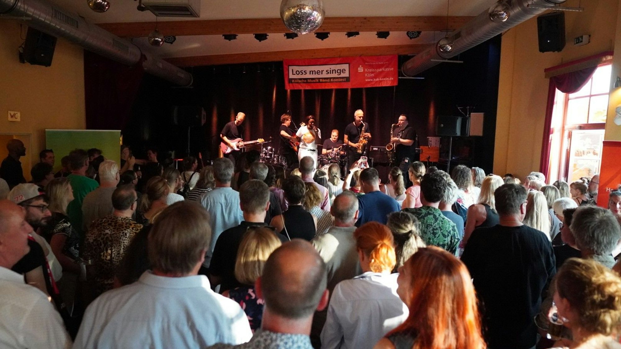 Ein Publikum steht vor einer Bühne mit Band.