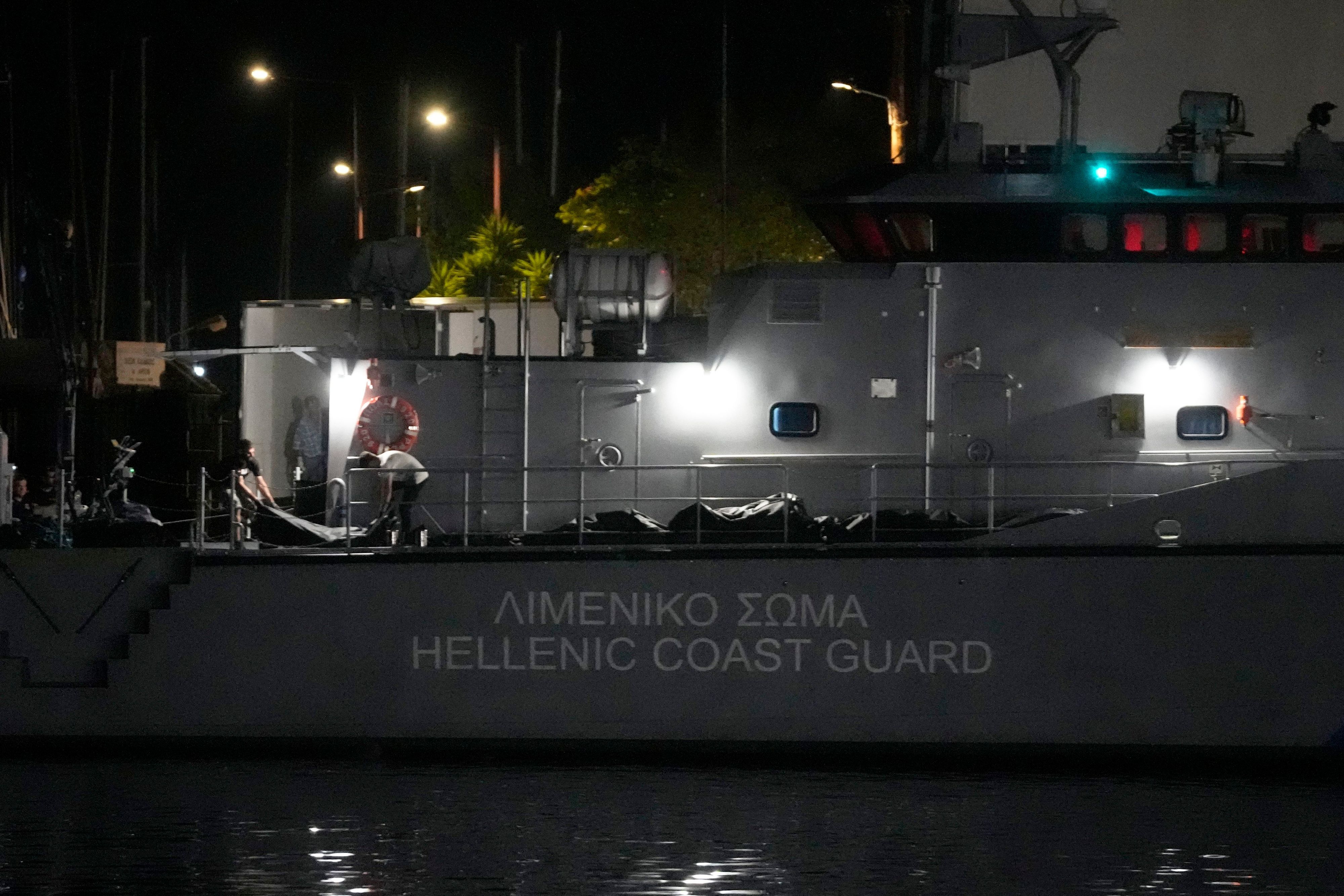 Rettungskräfte tragen Leichen von einem Schiff der Küstenwache in einen Kühlwagen im Hafen von Kalamata.