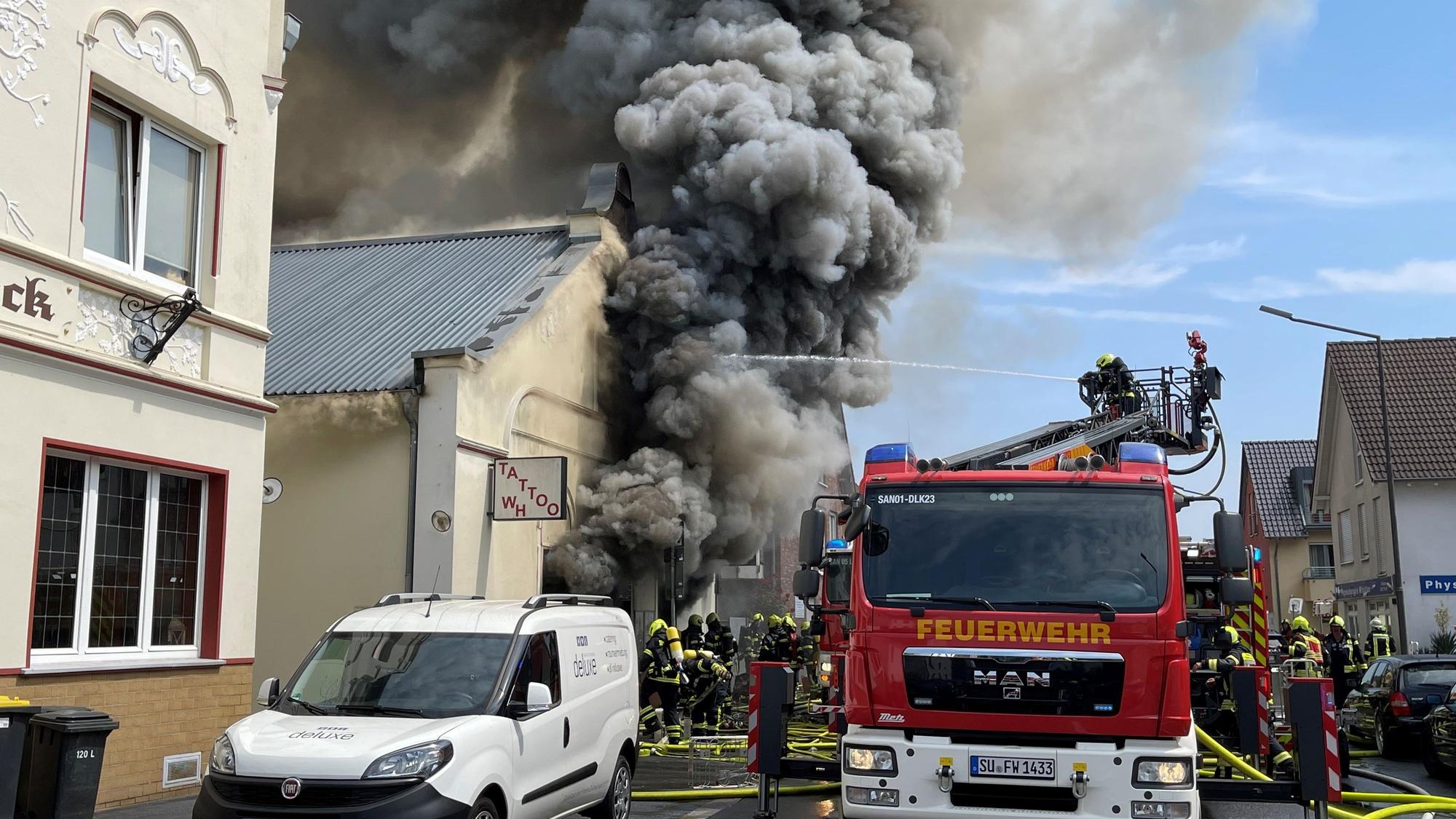 Mit der Drehleiter kämpften die Feuerwehrleute beim Brand eines Motorradladens in Sankt Augustin gegen den schwarzen Qualm und die Flammen an. Brand eines Motorradladens in Sankt Augustin auf der Hauptstraße an.