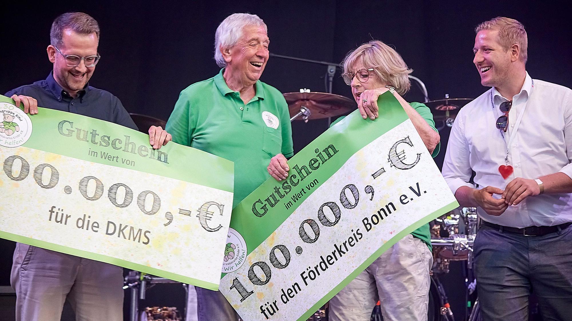 Mehrere Personen halten überdimensionierte Spenden-Gutscheine in den Händen und lachen.