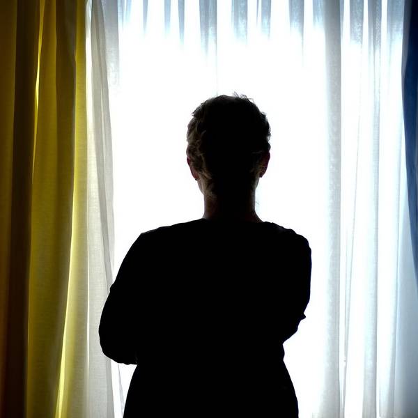 Eine junge Frau steht in einem Zimmer eines Frauenhauses (Symbolbild).