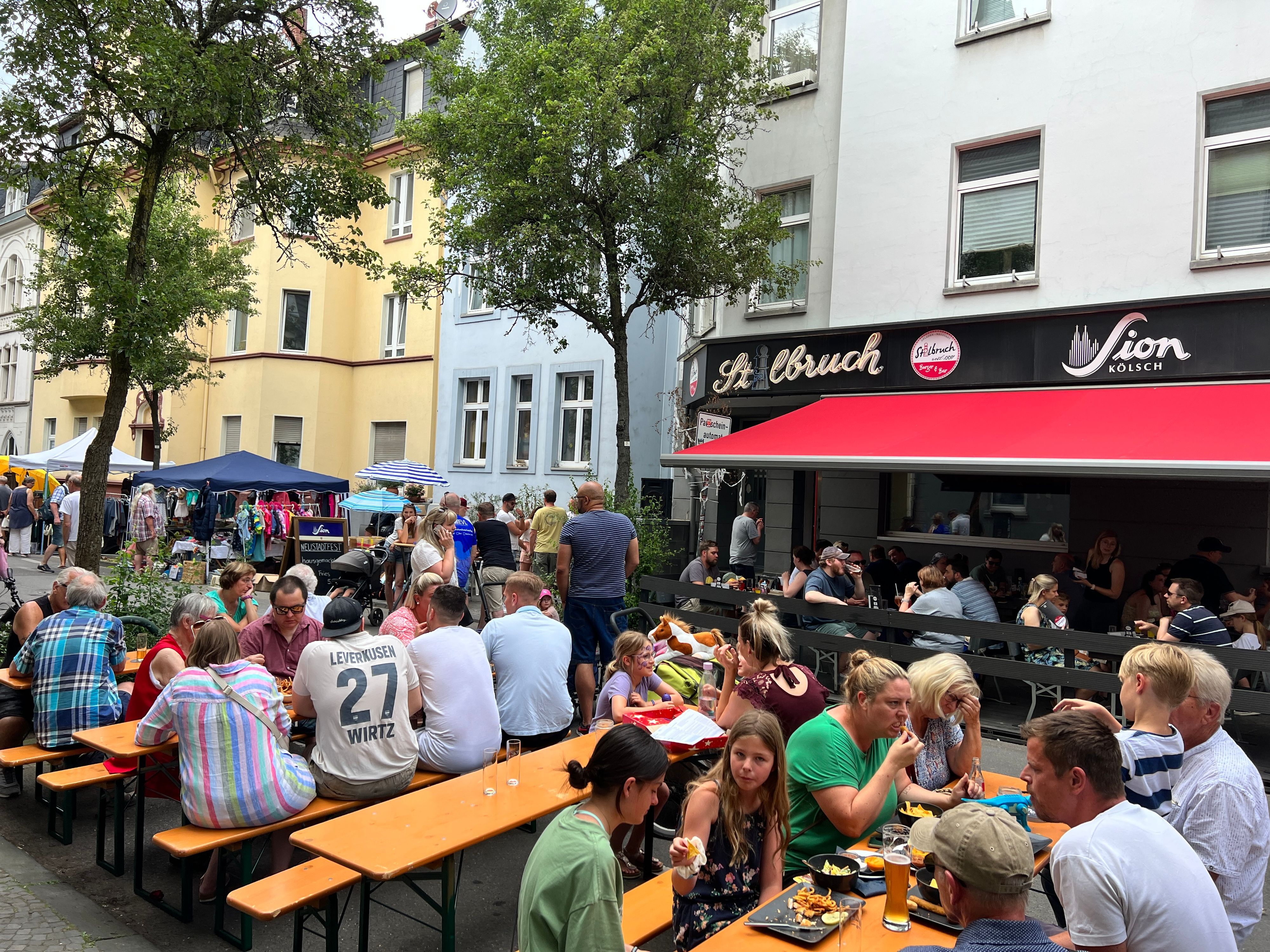 Menschen sitzen auf Bierbänken in Opladen.