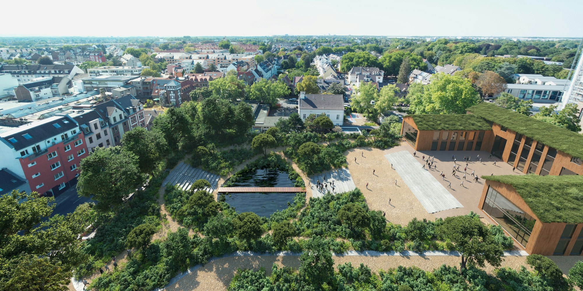 Luftbild zeigt ein Gelände mit einem Teich und einem Schulgebäude mit begrüntem Dach.