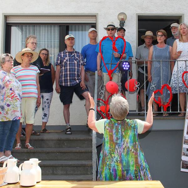 Mehrere Männer und Frauen, Mitglieder eines Chores, singen bei einem Fest in Schweinheim.